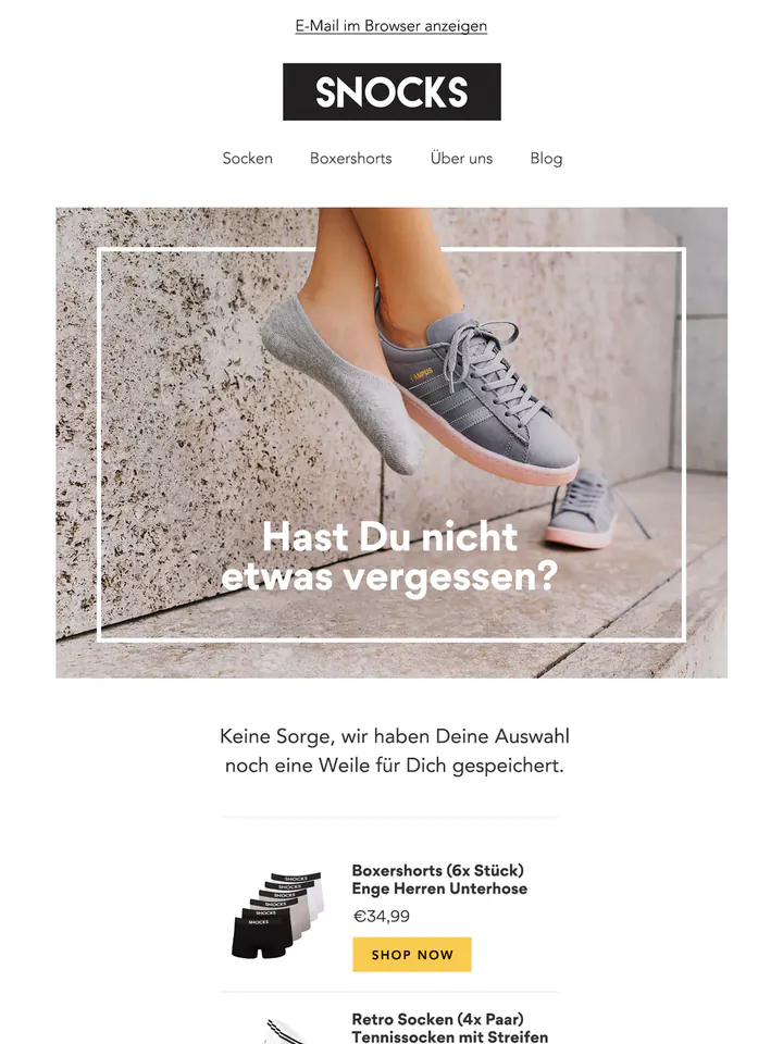 Snocks email in German: feet in grey invisible socks and trainers against a stone wall under the headline “Hast Du nicht etwas vergessen?”, above the saved boxer shorts and socks and a yellow button.