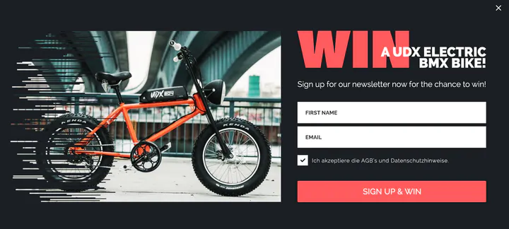 Urban Drivestyle pop-up: an orange UDX electric BMX bike under a bridge beside the coral headline “Win a UDX electric BMX bike!”, with first-name and email fields and a “Sign up & win” button.